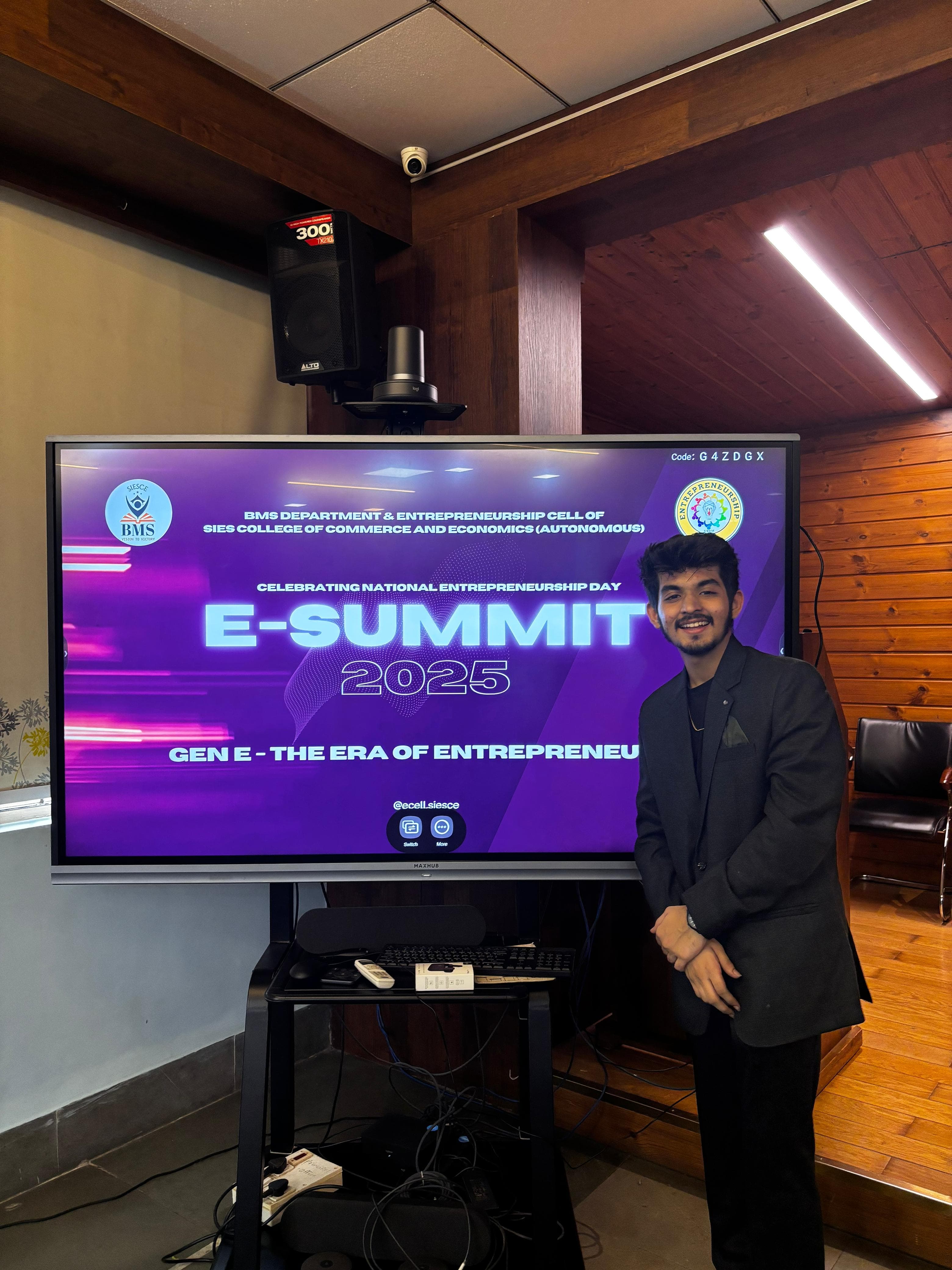 Romil Lodaya in a blazer beside an E-Summit 2025 screen at an entrepreneurship event