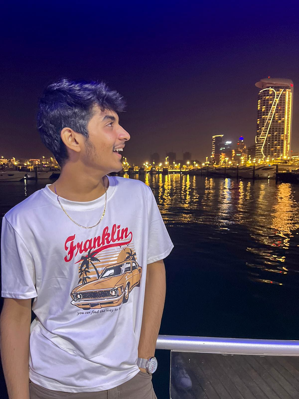 Romil Lodaya by a marina at night, city lights reflecting on the water