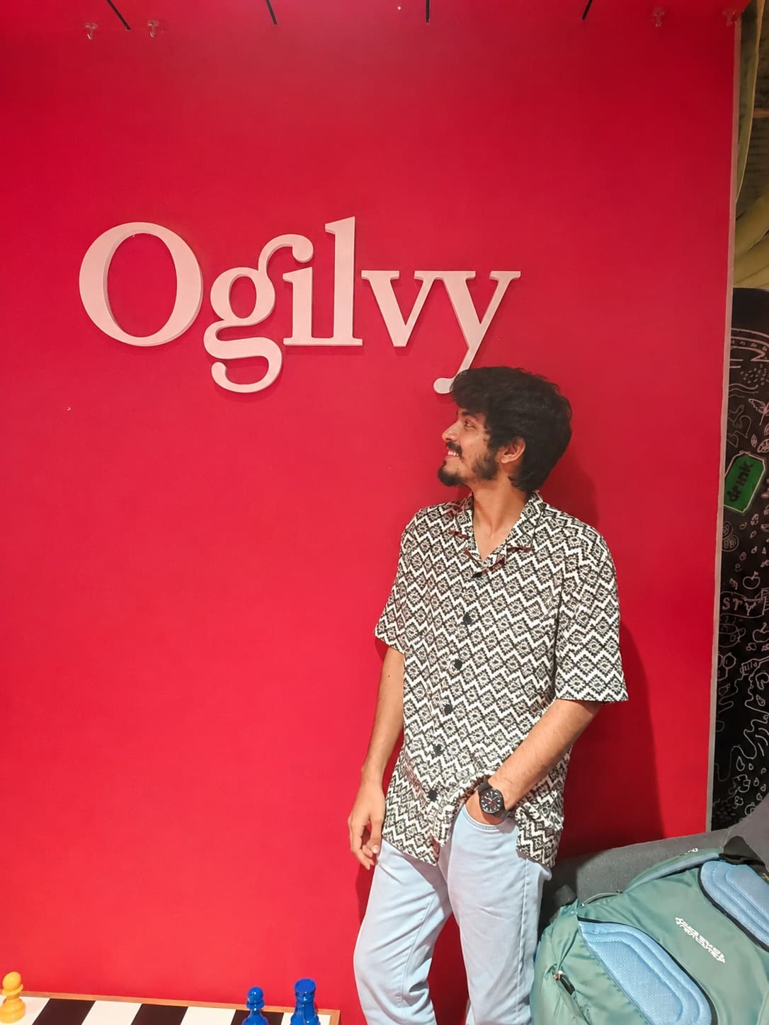 Romil Lodaya standing in front of a large red Ogilvy sign, looking up
