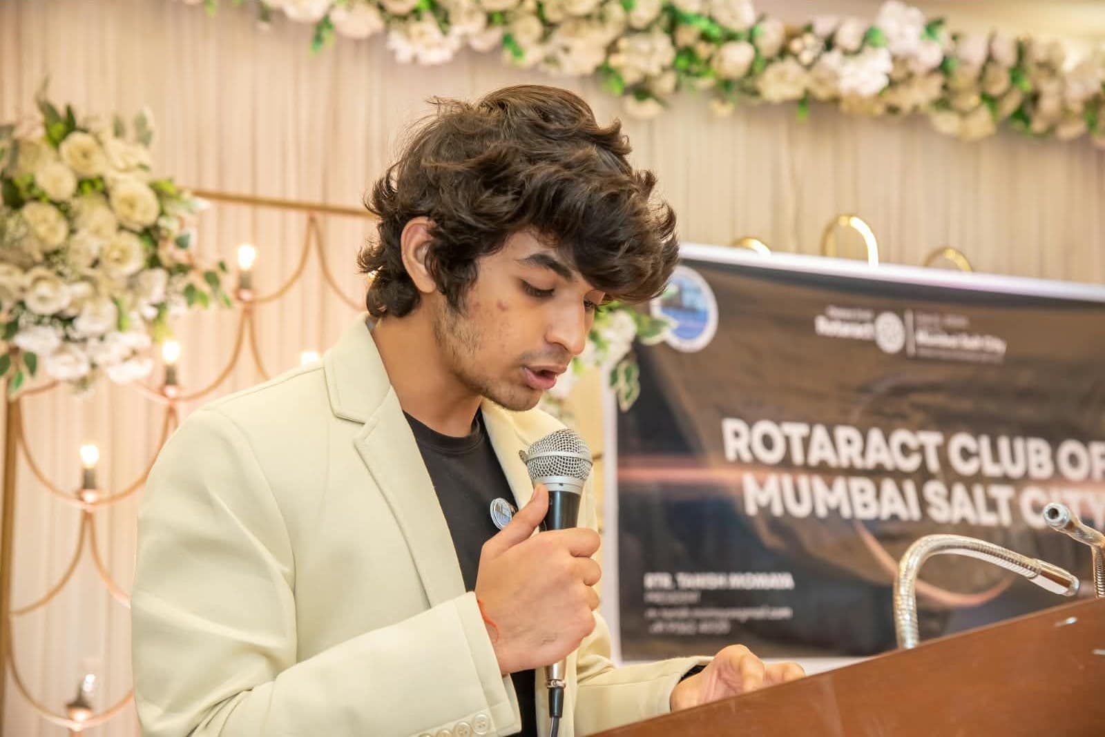 Romil Lodaya speaking into a microphone at a Rotaract Club of Mumbai Salt City podium